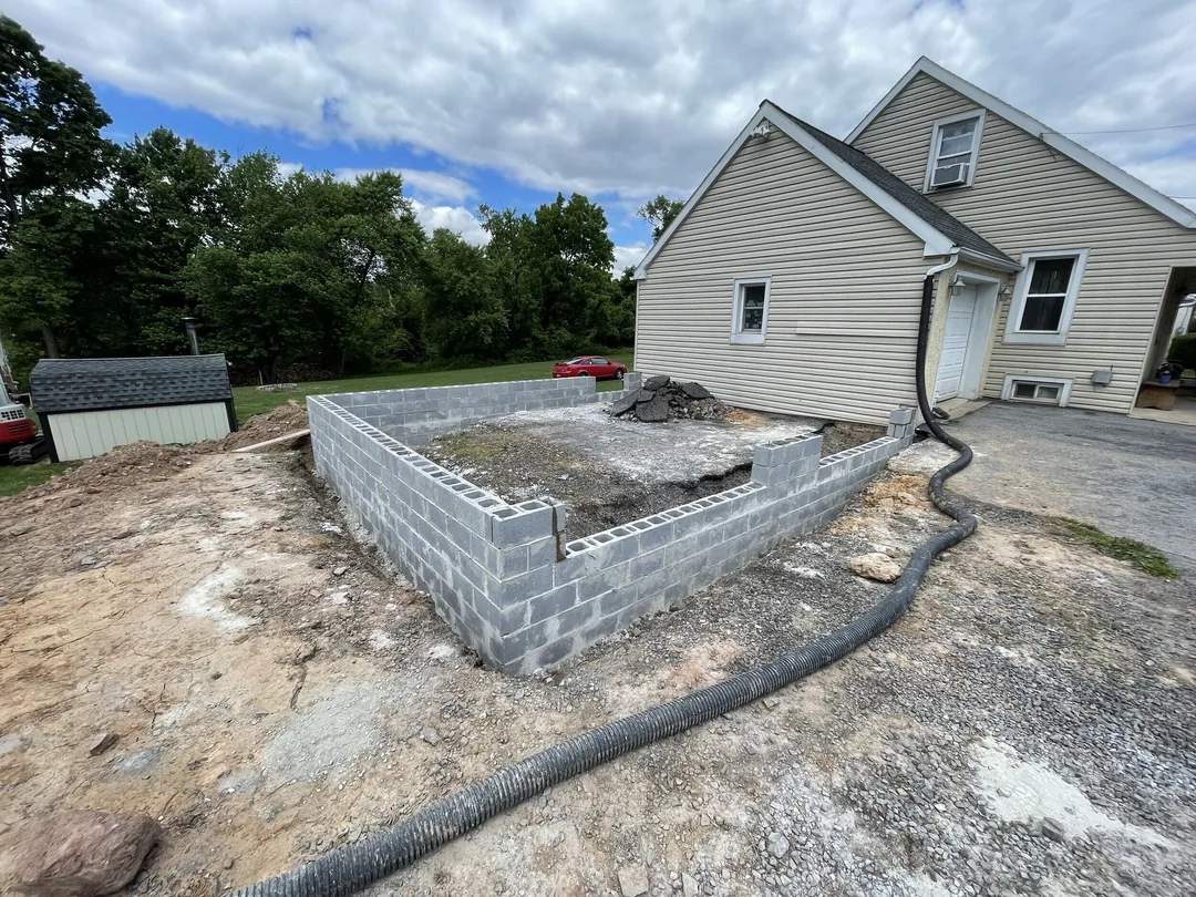 A freshly laid concrete block garage foundation beside a house, block walls