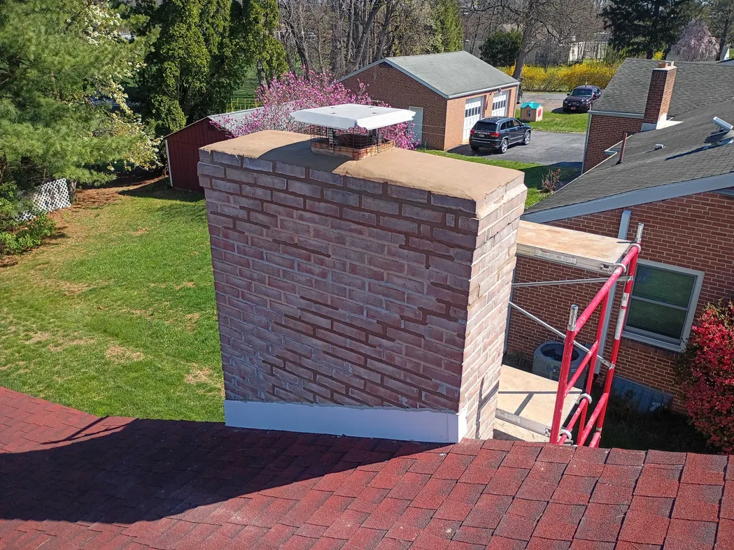 A brick chimney rebuilt above the roofline with a new crown and cap, brick masonry
