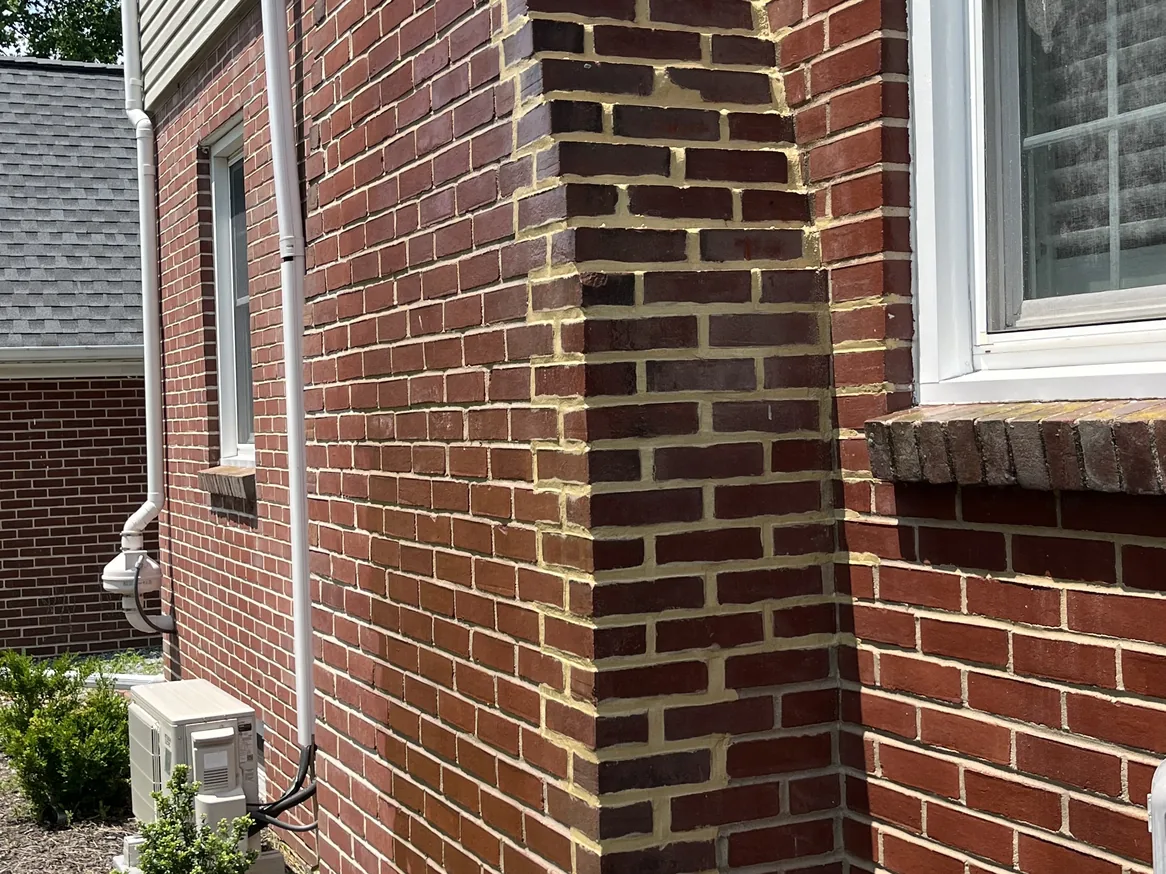 A brick chimney chase on a brick house with fresh mortar joints, brick repair