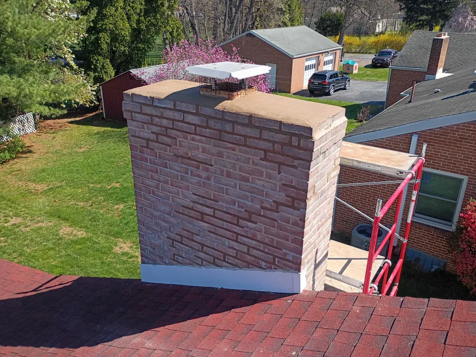 A brick chimney rebuilt above the roofline with a new crown and a cap, chimney repair