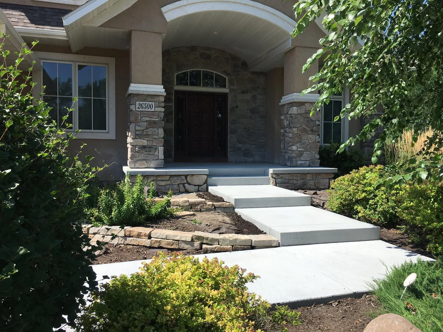 New concrete front steps and walk leading to a covered entry with stone columns, concrete work
