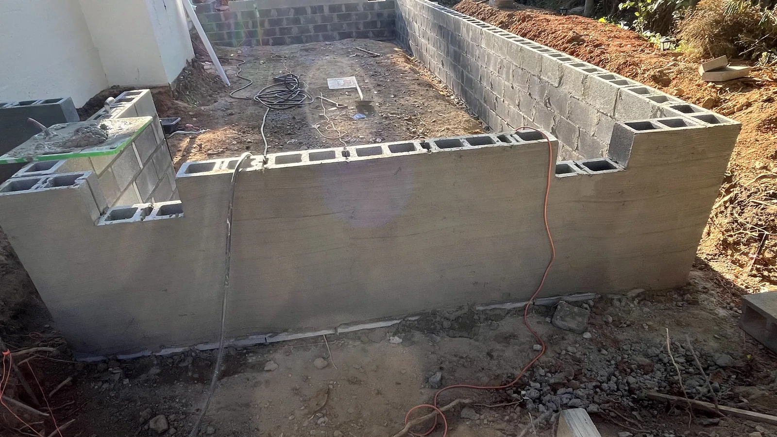 Concrete block foundation walls beside a house, masonry contractor work