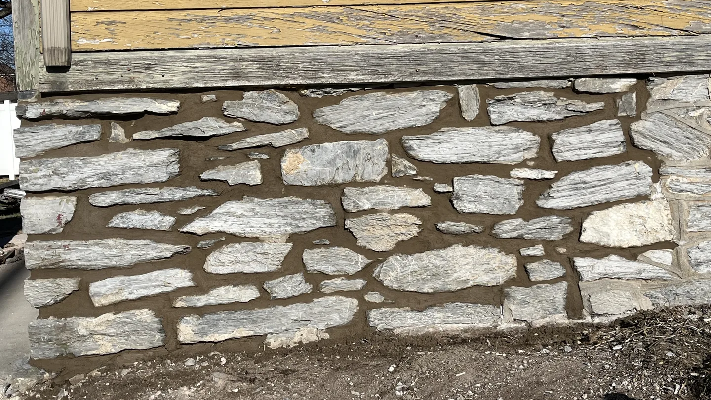 An old stone foundation wall with fresh mortar joints, masonry contractor work