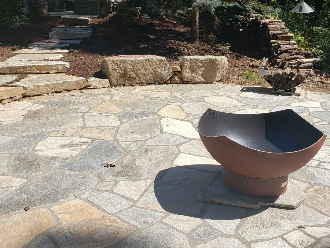A natural flagstone patio with a steel fire bowl and stone slab steps, brick and stone patios