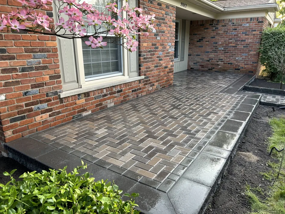 A herringbone brick paver patio along the front of a brick house, brick and stone patios