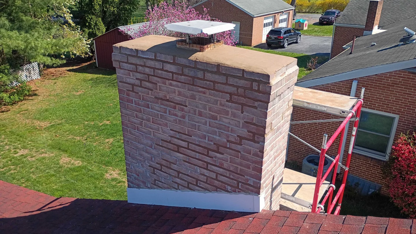 A rebuilt brick chimney on a home overlooking neighboring yards, masonry contractor work