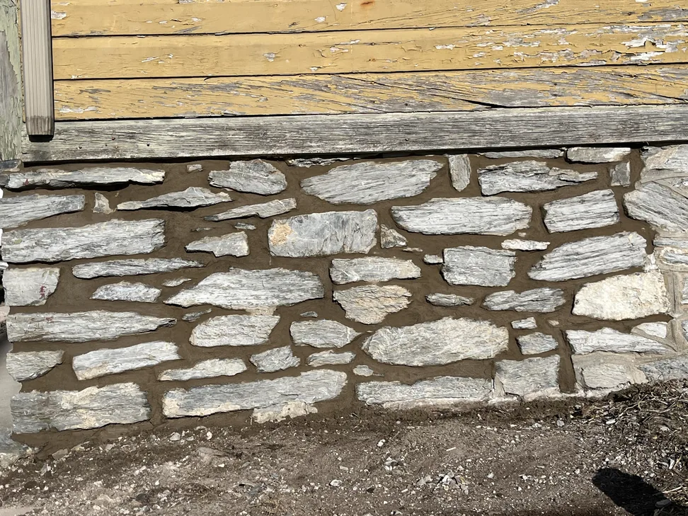A stone foundation wall repointed with fresh mortar joints, tuckpointing